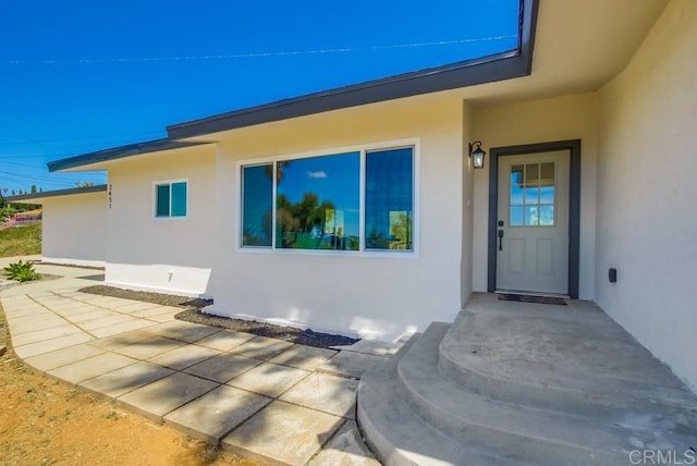 property entrance featuring stucco siding and a patio