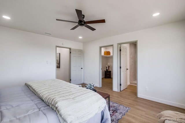 bedroom with baseboards, recessed lighting, light wood-style flooring, ceiling fan, and a spacious closet