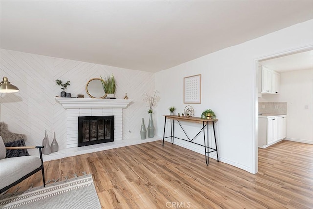 15821 Willett Ln, Huntington Beach, CA 92647 - living area featuring light wood-type flooring, a brick fireplace, and baseboards