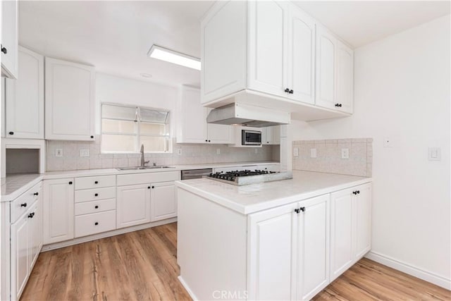 15821 Willett Ln, Huntington Beach, CA 92647 - kitchen with a sink, light wood-style floors, wall chimney exhaust hood, decorative backsplash, and a peninsula