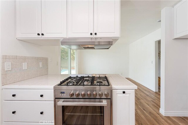 15821 Willett Ln, Huntington Beach, CA 92647 - kitchen featuring under cabinet range hood, high end range, light countertops, and light wood-style flooring