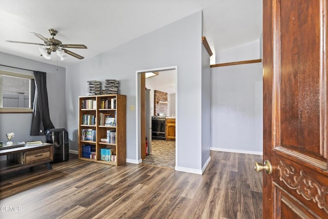 interior space with dark wood-style flooring, a ceiling fan, and baseboards