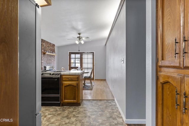 kitchen featuring electric range, freestanding refrigerator, ceiling fan, tile counters, and brown cabinetry