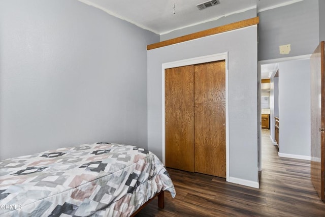 bedroom with wood finished floors, baseboards, and a closet