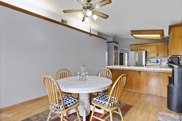 dining area with light wood-style flooring and ceiling fan