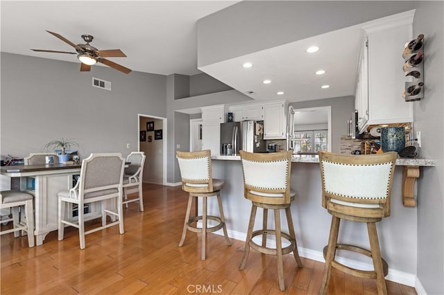 41488 Yankee Run Ct, Temecula, CA 92591 - kitchen featuring stainless steel fridge, ceiling fan, white cabinets, light wood-style flooring, and a peninsula