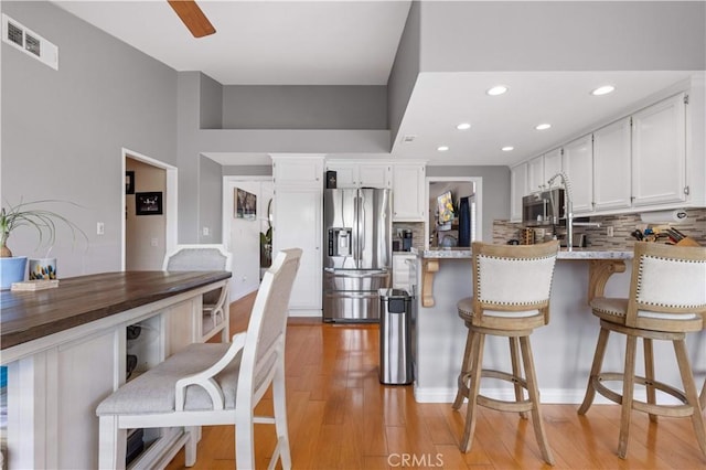 41488 Yankee Run Ct, Temecula, CA 92591 - kitchen featuring stainless steel appliances, backsplash, white cabinets, a peninsula, and recessed lighting
