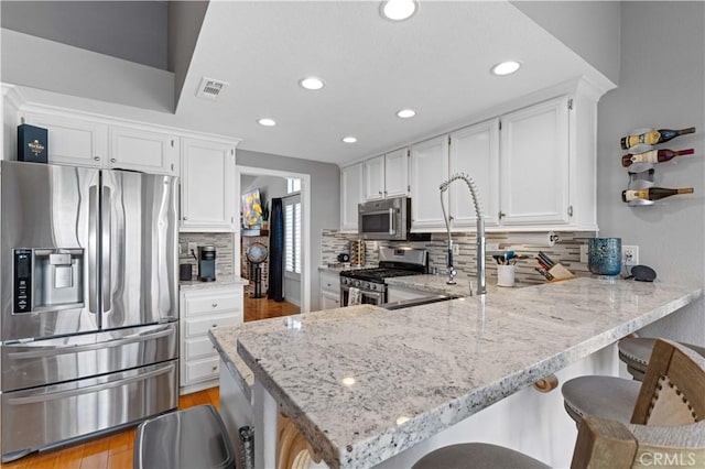 41488 Yankee Run Ct, Temecula, CA 92591 - kitchen featuring stainless steel appliances, decorative backsplash, light stone countertops, white cabinetry, and recessed lighting