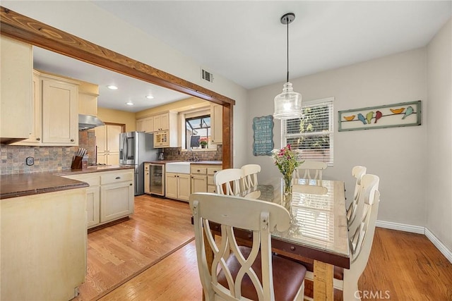 dining space featuring wine cooler, light wood-type flooring, healthy amount of natural light, recessed lighting, and baseboards