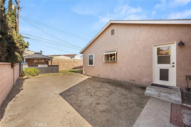 back of house with a gazebo, stucco siding, a fenced backyard, crawl space, and a patio
