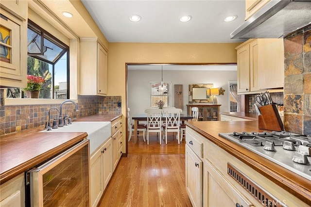 kitchen with wine cooler, stainless steel gas stovetop, recessed lighting, extractor fan, and a sink