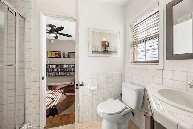 ensuite bathroom with a stall shower, ceiling fan, toilet, tile walls, and vanity