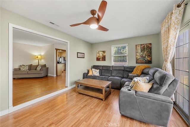 living area with a ceiling fan, light wood-style floors, and baseboards