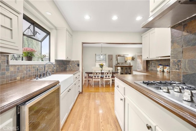 1418 S Cedar Ave, Fullerton, CA 92833 - kitchen with beverage cooler, wall chimney exhaust hood, backsplash, recessed lighting, and white cabinets