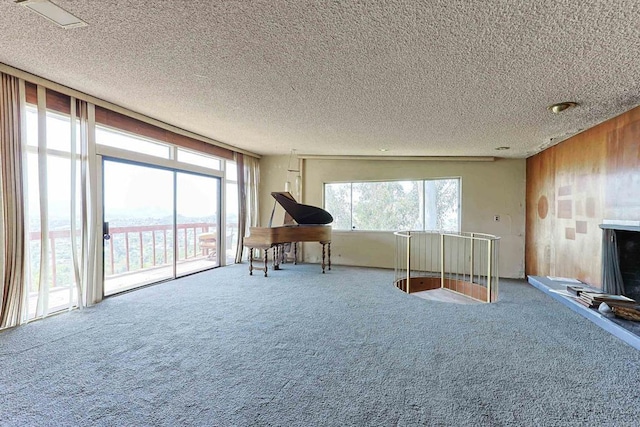 living area with carpet floors, wood walls, and a textured ceiling