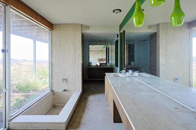 full bath with unfinished concrete flooring, vanity, plenty of natural light, and a textured ceiling
