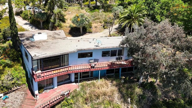 back of house featuring a wooden deck and view of wooded area