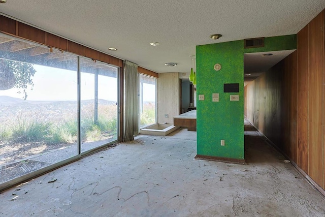 spare room featuring a textured ceiling, wood walls, and a mountain view