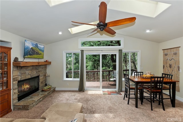 23776 Lakeview Dr, Crestline, CA 92325 - dining area with a skylight, vaulted ceiling, carpet flooring, ceiling fan, and a stone fireplace