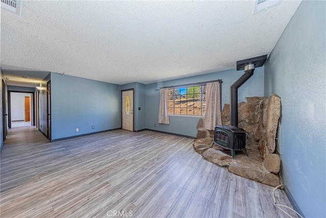 43096 Deer Trail Way, Coarsegold, CA 93614 - unfurnished living room with a textured ceiling, a wood stove, wood finished floors, and baseboards