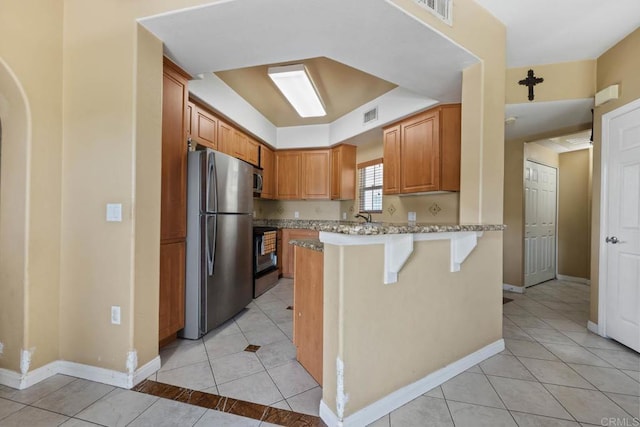 2707 Lake Pointe Dr Unit 204, Spring Valley, CA 91977 - kitchen featuring freestanding refrigerator, a peninsula, light tile patterned flooring, a kitchen breakfast bar, and stove