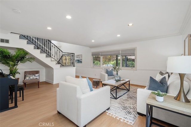 living area featuring stairs, baseboards, light wood-style flooring, recessed lighting, and ornamental molding
