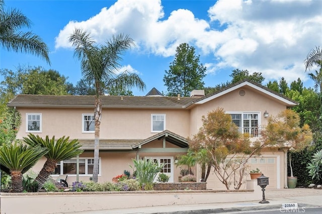 view of front facade with stucco siding, a garage, and driveway