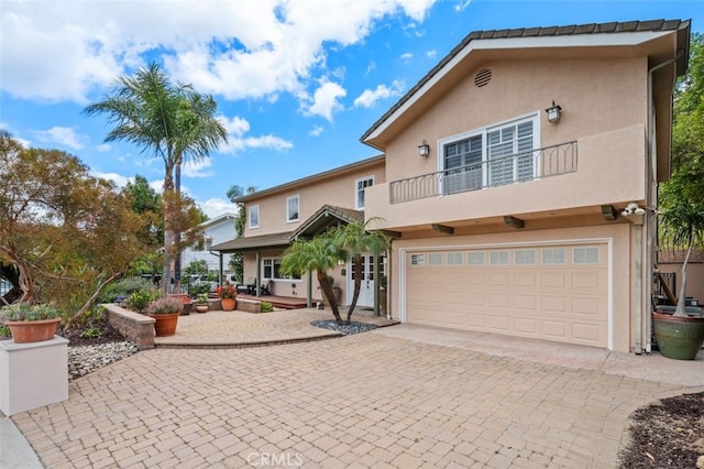 view of front of home with stucco siding, decorative driveway, and a balcony