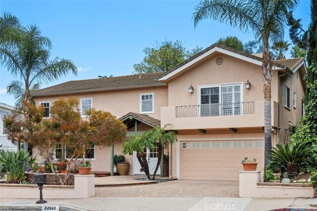 view of front of home featuring a balcony, stucco siding, a garage, and driveway