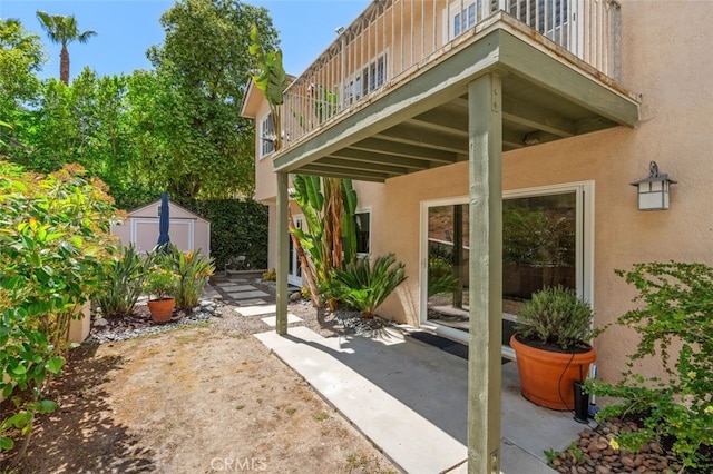 doorway to property with a balcony, stucco siding, and a patio