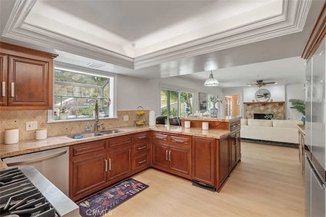 kitchen featuring a raised ceiling, light wood-style floors, a fireplace, a sink, and light stone countertops