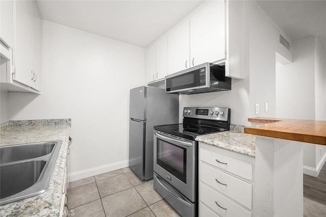 448 N Bellflower Blvd Unit 119, Long Beach, CA 90814 - kitchen featuring stainless steel appliances, baseboards, light countertops, and white cabinets