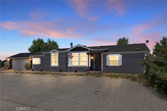 single story home with roof mounted solar panels, a garage, and driveway