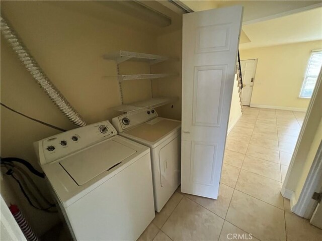 laundry room with independent washer and dryer, light tile patterned flooring, and baseboards