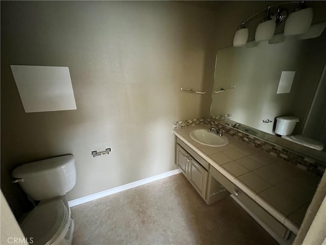 bathroom with toilet, vanity, and baseboards