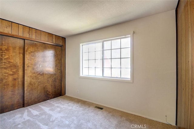 221 E Barker Blvd, Big Bear City, CA 92314 - unfurnished bedroom featuring carpet, wood walls, a closet, and baseboards