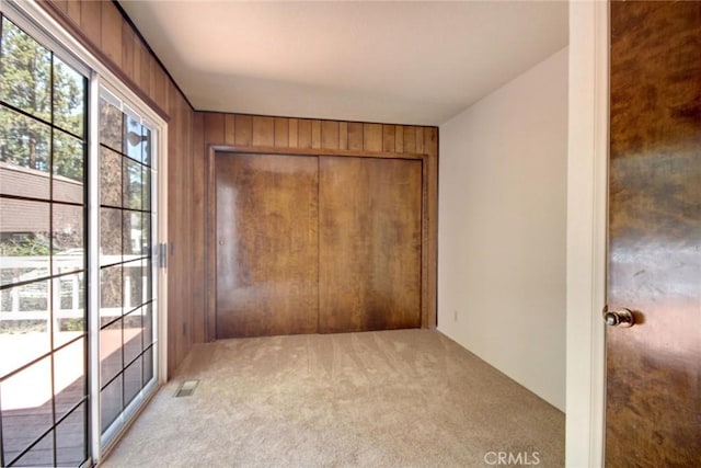 221 E Barker Blvd, Big Bear City, CA 92314 - unfurnished bedroom featuring light carpet, wood walls, a closet, and access to exterior