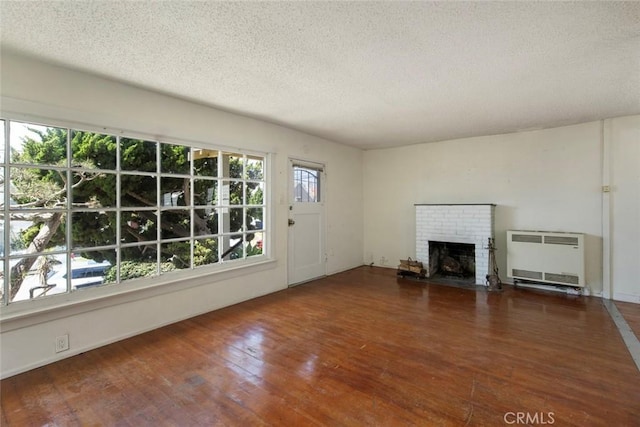 808 El Redondo Ave, Redondo Beach, CA 90277 - unfurnished living room featuring heating unit, a textured ceiling, wood-type flooring, a fireplace, and radiator heating unit