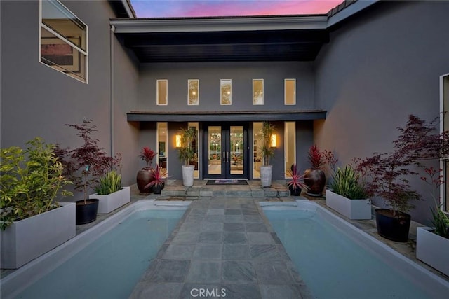 18782 Peppertree Dr, Villa Park, CA 92861 - exterior entry at dusk with french doors, stucco siding, an outdoor pool, and a patio