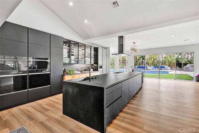 18782 Peppertree Dr, Villa Park, CA 92861 - kitchen with wall chimney exhaust hood, modern cabinets, light wood-type flooring, a spacious island, and gray cabinets