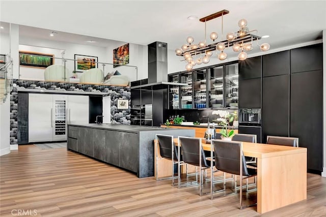 18782 Peppertree Dr, Villa Park, CA 92861 - kitchen with dark cabinetry, light wood finished floors, glass insert cabinets, recessed lighting, and a chandelier