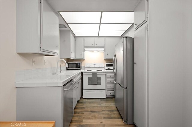 1015 N Michillinda Ave Unit 104, Pasadena, CA 91107 - kitchen featuring stainless steel appliances, under cabinet range hood, a sink, wood finished floors, and tile counters