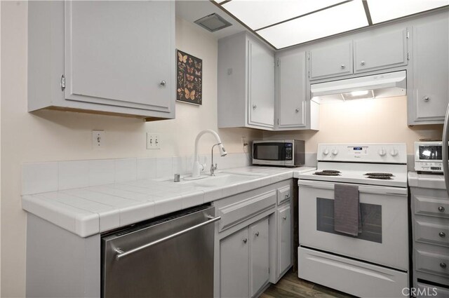 1015 N Michillinda Ave Unit 104, Pasadena, CA 91107 - kitchen with appliances with stainless steel finishes, under cabinet range hood, a sink, dark wood-type flooring, and gray cabinetry