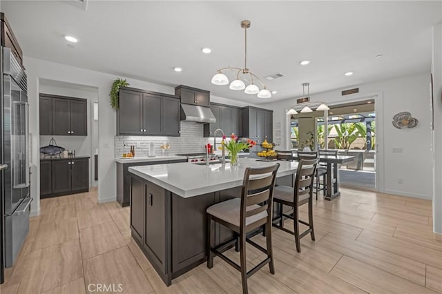 32404 Old Sage Dr, San Juan Capistrano, CA 92675 - kitchen with stainless steel built in fridge, backsplash, light countertops, a center island with sink, and under cabinet range hood