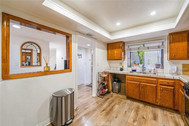 365 W Alameda Ave Unit 203, Burbank, CA 91506 - kitchen with a sink, light wood-type flooring, baseboards, brown cabinetry, and a tray ceiling