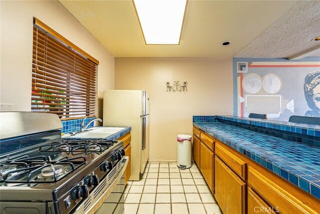 365 W Alameda Ave Unit 203, Burbank, CA 91506 - kitchen with gas range, a sink, brown cabinetry, tile countertops, and light tile patterned flooring