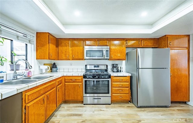 365 W Alameda Ave Unit 203, Burbank, CA 91506 - kitchen featuring appliances with stainless steel finishes, a sink, a tray ceiling, and tile counters