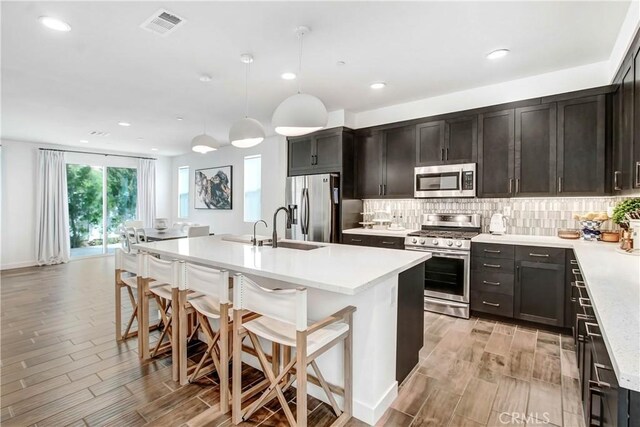 11837 Terra Vista Way, Sylmar, CA 91342 - kitchen with appliances with stainless steel finishes, a sink, wood finish floors, tasteful backsplash, and recessed lighting
