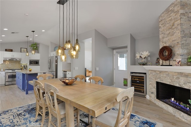 24632 Stagg St, West Hills, CA 91304 - dining room featuring beverage cooler, lofted ceiling, light wood-type flooring, a fireplace, and recessed lighting