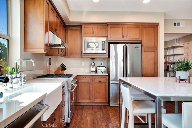 1508 W Artesia Unit H, Gardena, CA 90248 - kitchen featuring premium appliances, under cabinet range hood, brown cabinets, recessed lighting, and dark wood-type flooring